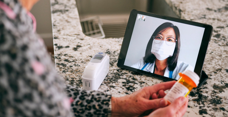 woman holding prescription bottle during video call with medical professional