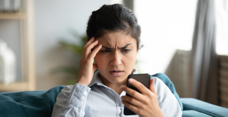 Girl frowning while looking at cell phone