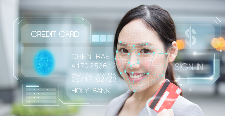 A young adult holding a credit card has recognition points portrayed on their face with credit card information displayed in the background.