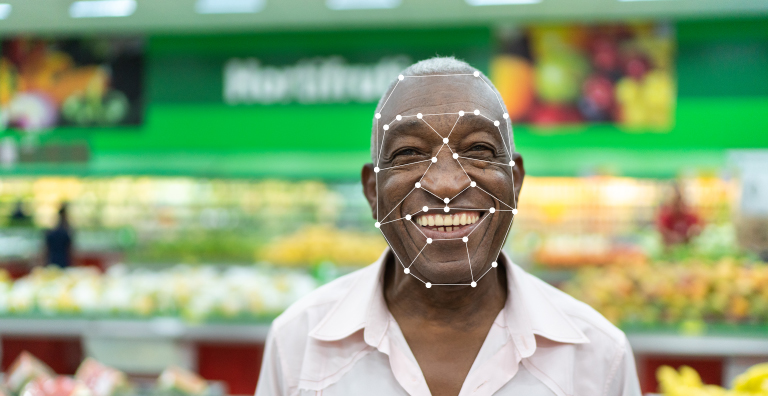 A grocery store customer smiling with a facial recognition graphic over their face.