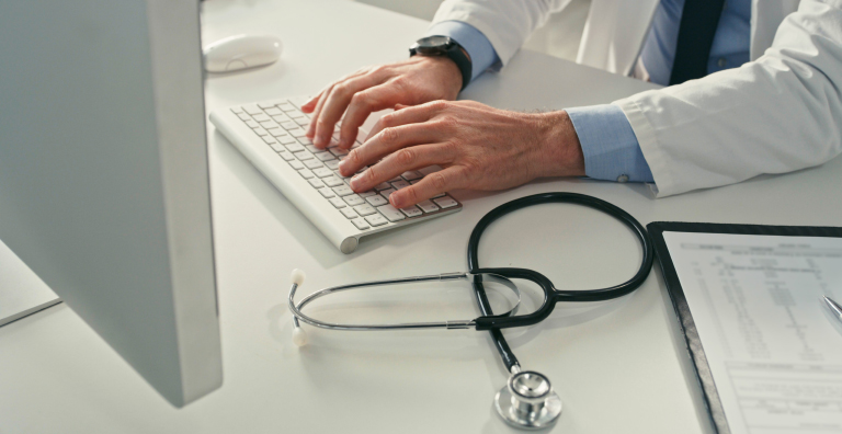 medical professional typing on laptop
