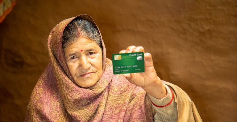 Elderly woman holding a credit card, highlighting accessibility and trust in fingerprint biometrics to illustrate the financial inclusion concept.